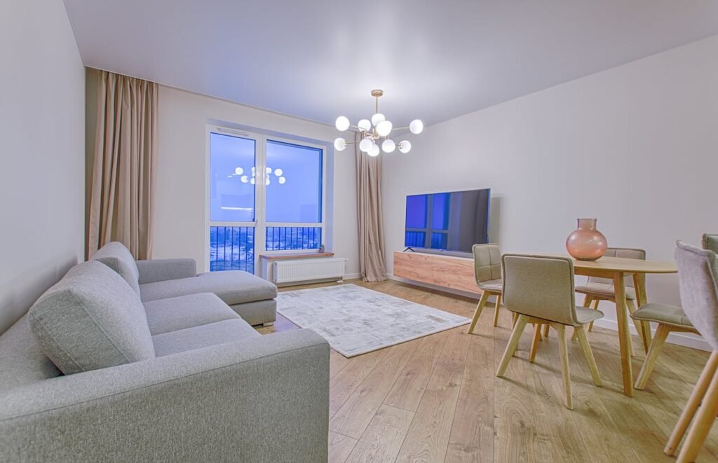 chandelier lights hanging at ceiling with sofa sets, doors and chairs in a room