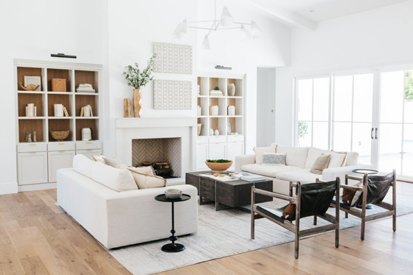 2 white sofas, 2 white book shelf, 2 chairs and a table in the room.