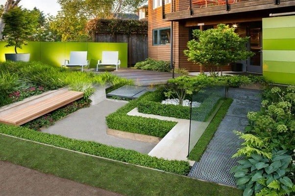 a garden in front of the house where few chairs, trees.