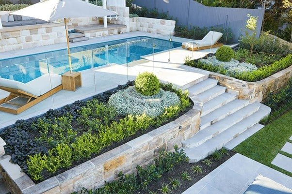 poolside lovely decorated by greenery with beautiful trees and seating area.