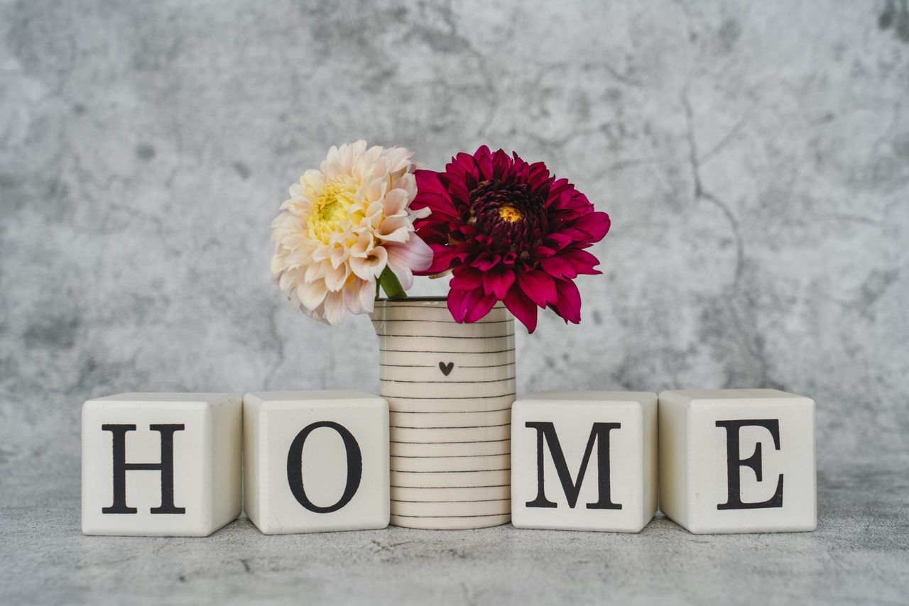 Elegant home decor featuring dahlias in a vase with decorative blocks spelling 'HOME'.
